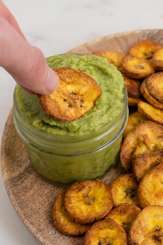 Close-up shot of a plantain chip dipped in guacamole