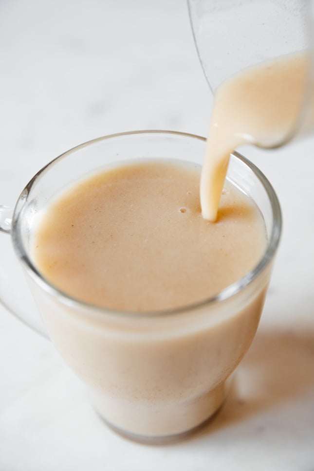 A picture of someone pouring rice milk into a glass jar