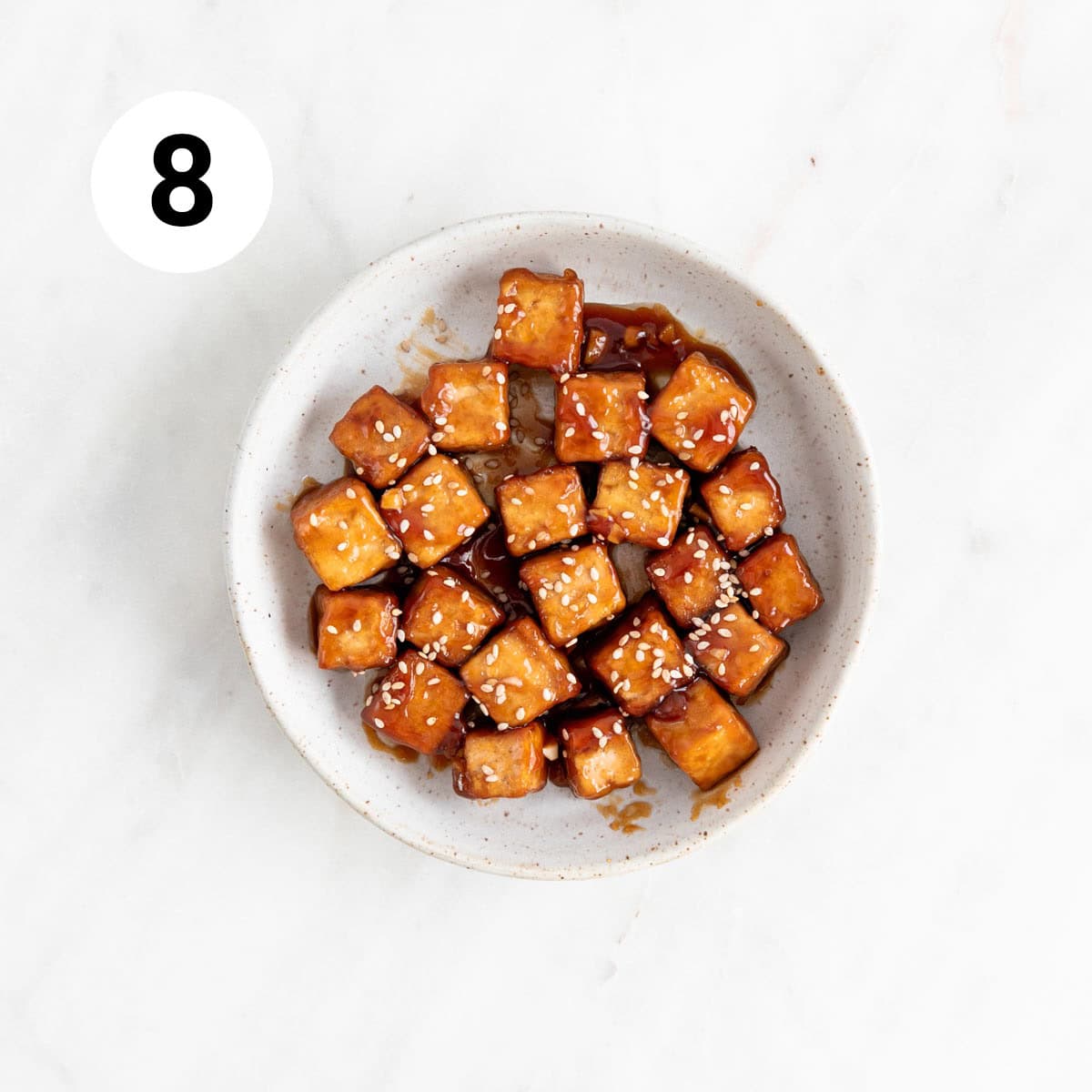 Crispy sesame tofu in a dish garnished with sesame seeds.