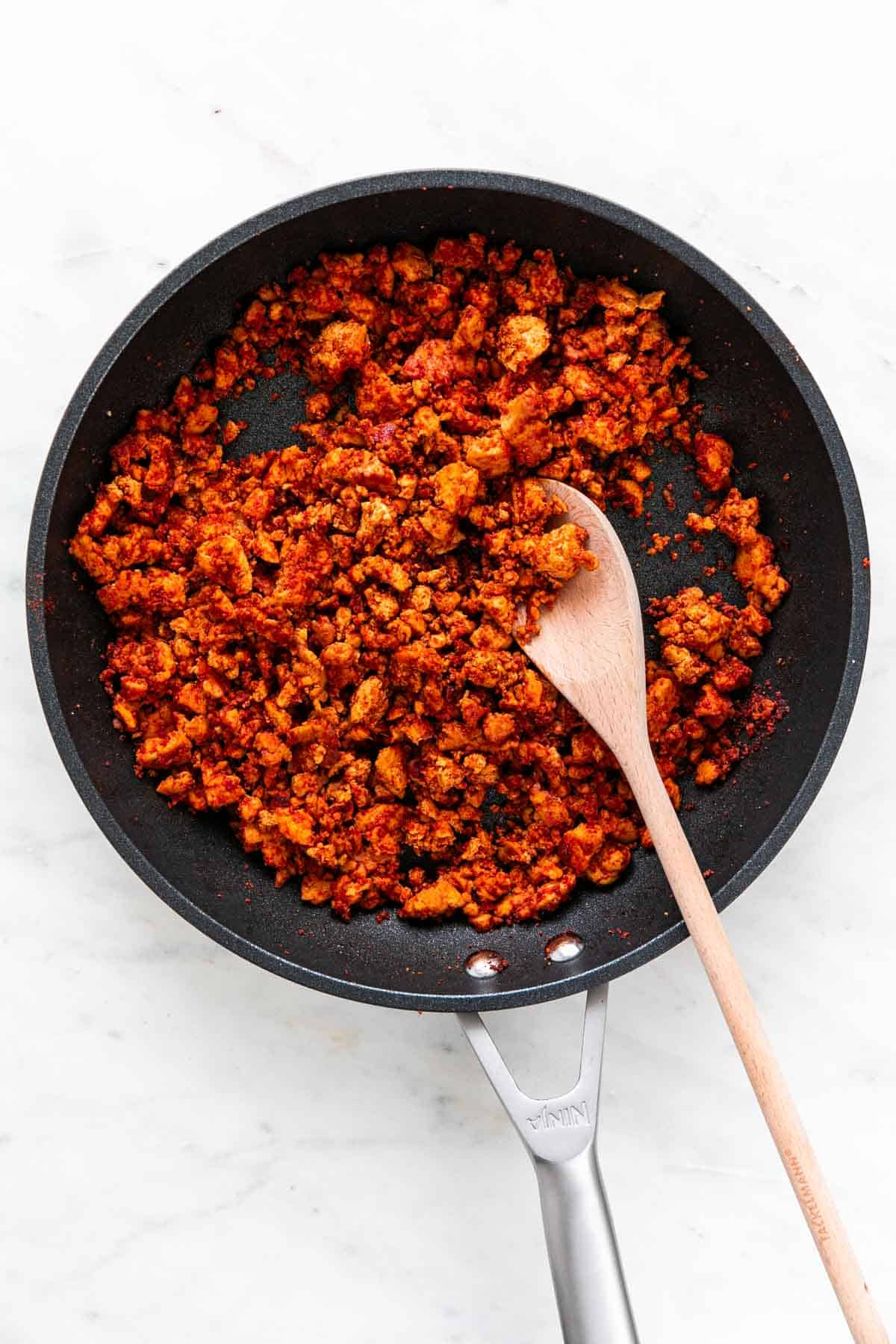 Soyrizo in a skillet with a wooden spoon.