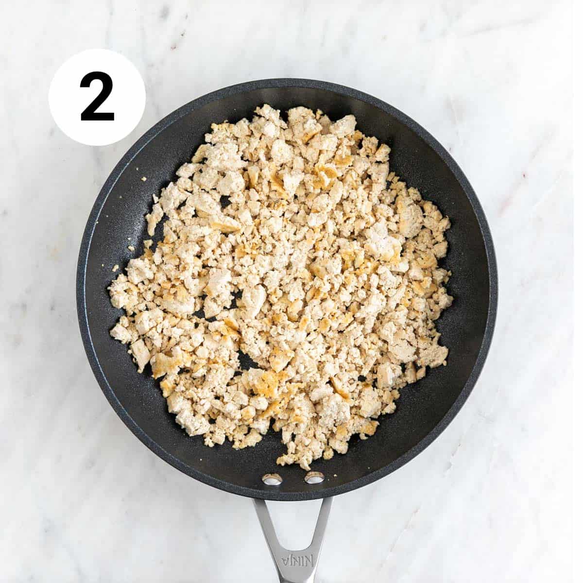 Crumbled tofu cooking in a skillet.