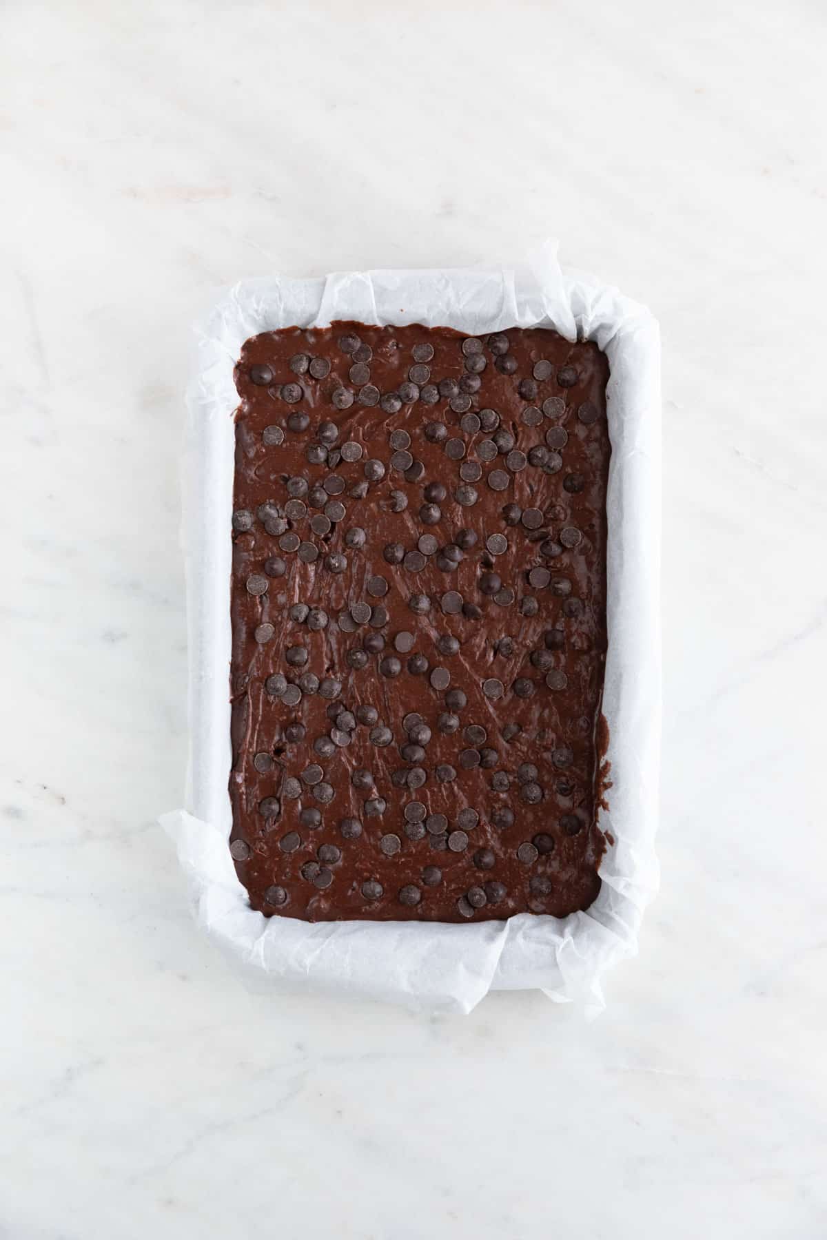 Vegan brownie batter in a lined pan.