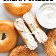 Bagels, some topped with vegan cream cheese, and a bowl with more vegan cream cheese.
