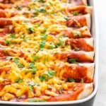 Vegan enchiladas in a baking dish with chopped cilantro on top