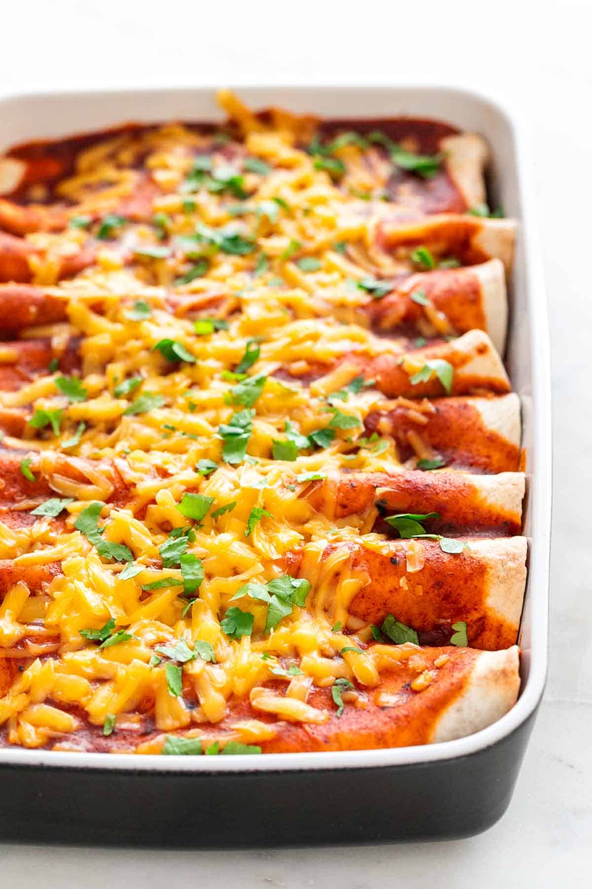 Baking dish of vegan enchiladas with chopped cilantro on top.