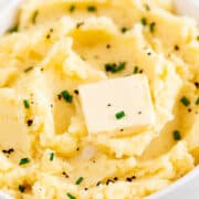 Bowl of vegan mashed potatoes, vegan butter, chives, and pepper garnish.