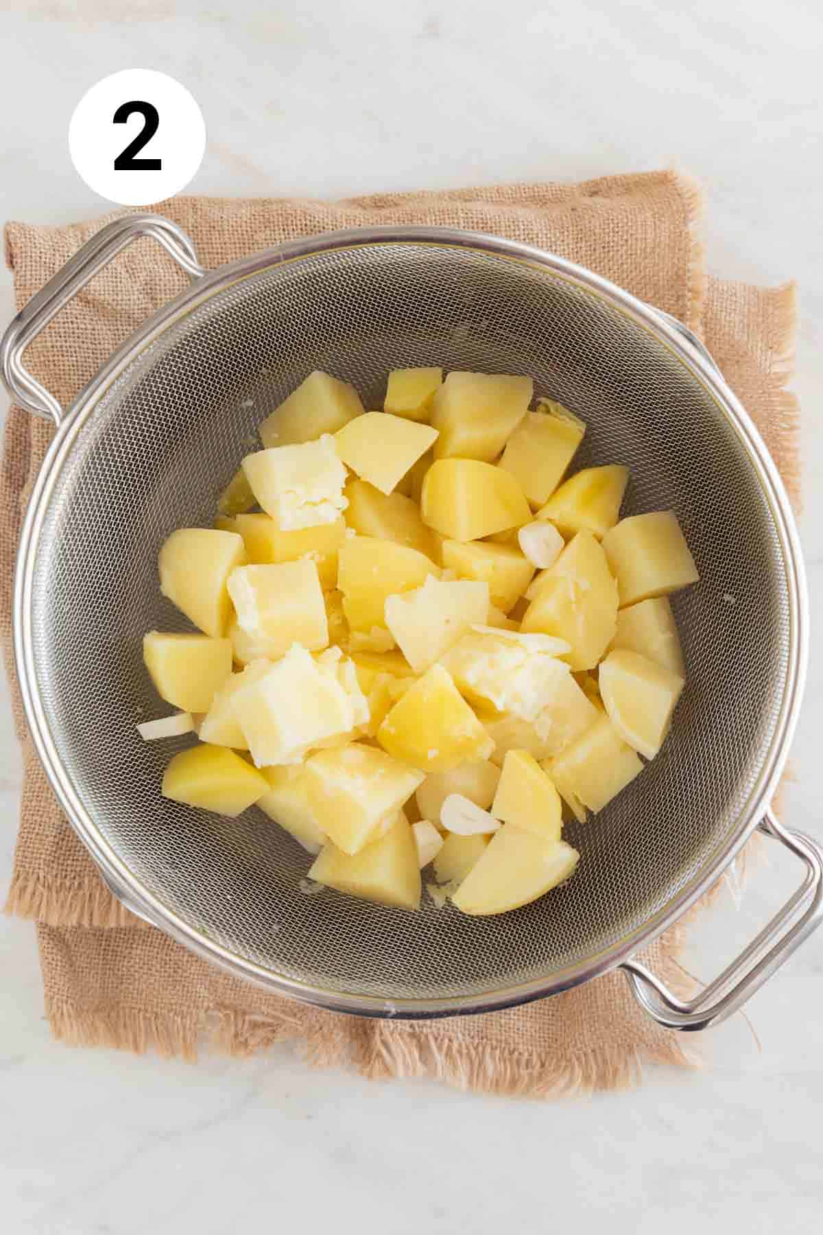 Cooked potatoes and garlic in a strainer onto a large pot.