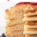 Stack of vegan pancakes sliced open to reveal a fluffy interior, topped with strawberries and blueberries.