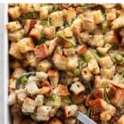 Baking dish with vegan stuffing and a spoon.