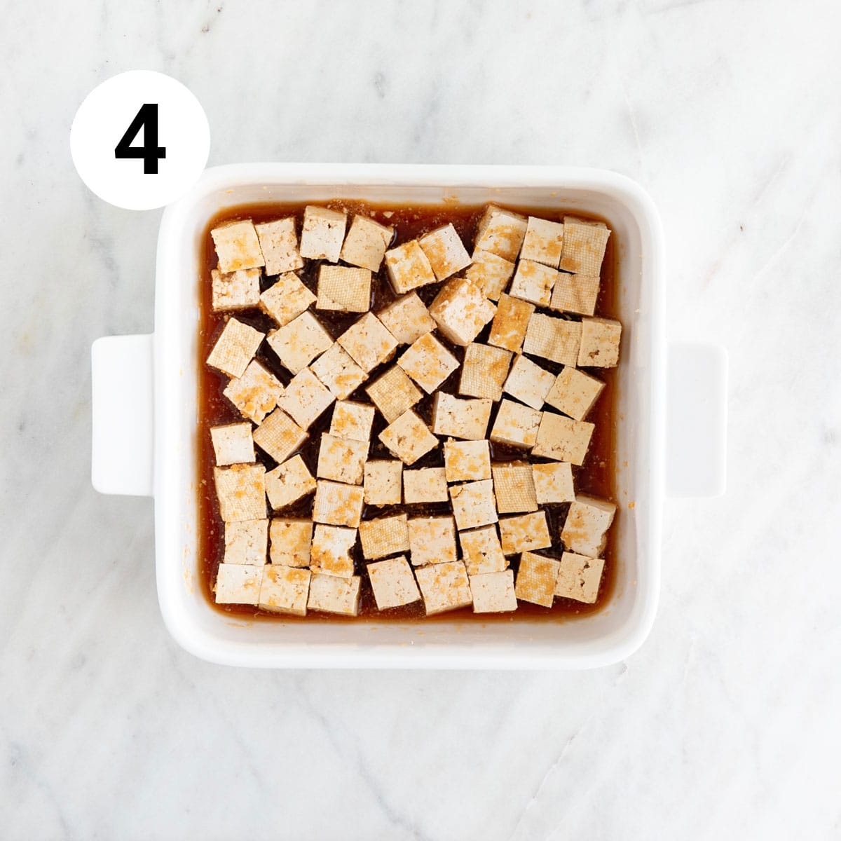 Tofu cubes marinating in a baking dish.
