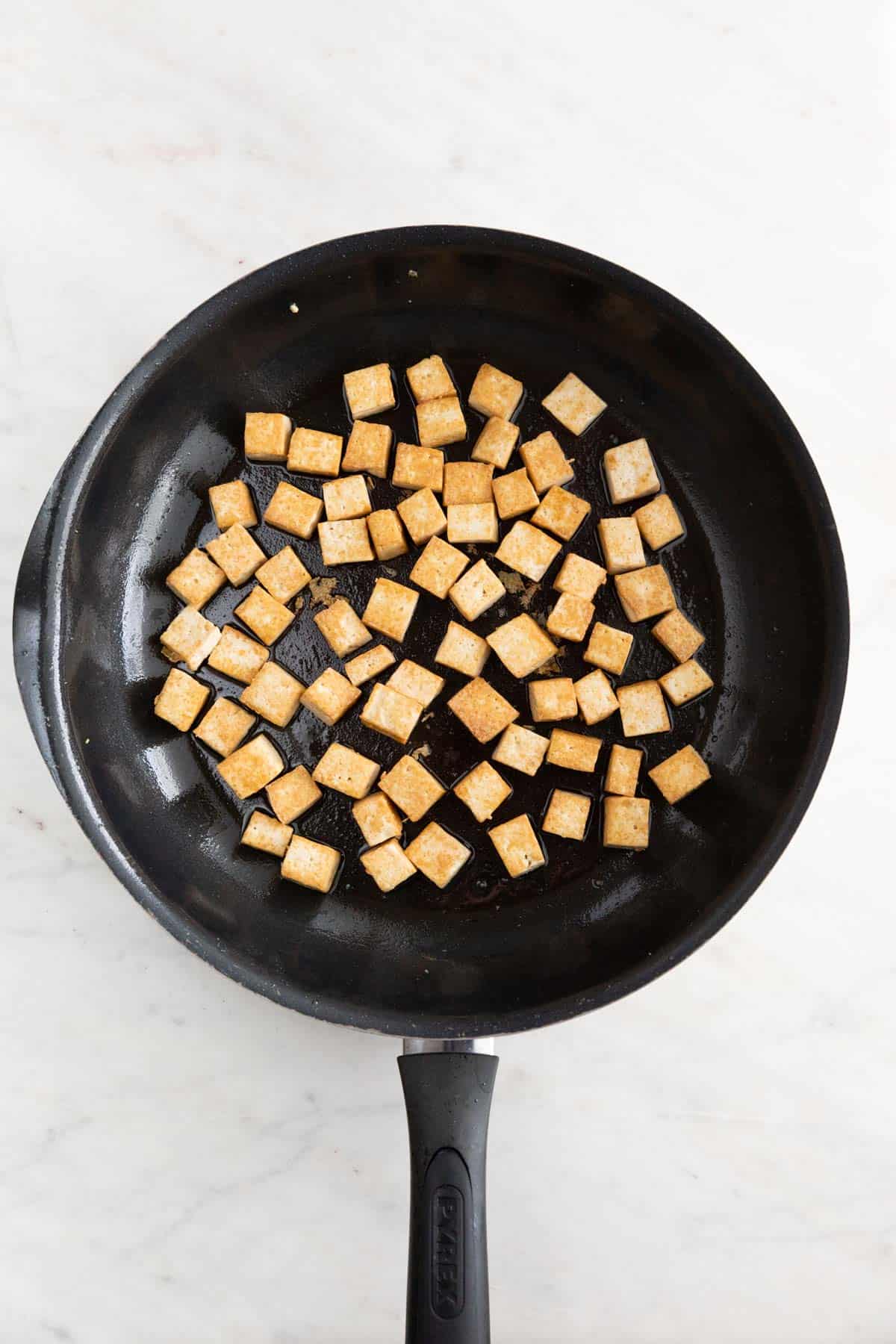 Sautéed tofu cubes in a skillet.