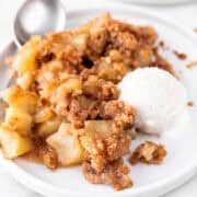 Plate of vegan apple crisp, vegan vanilla ice cream, and spoon.