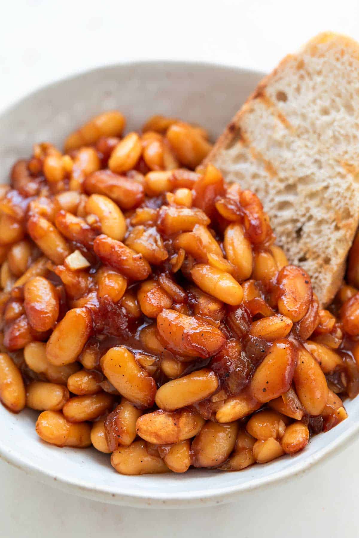 Bowl of vegan baked beans with a slice of bread.