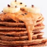 Vegan banana pancakes stack with peanut butter, chocolate chips, and sliced banana.