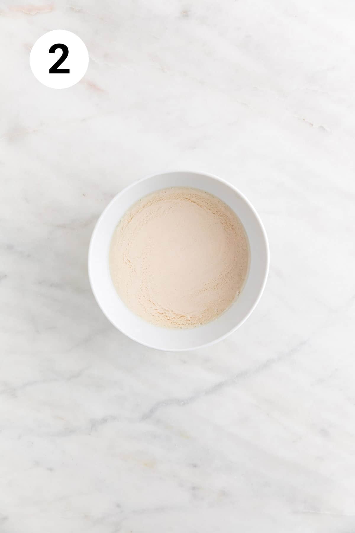 Mixture of non-dairy milk and apple cider vinegar in a small bowl.