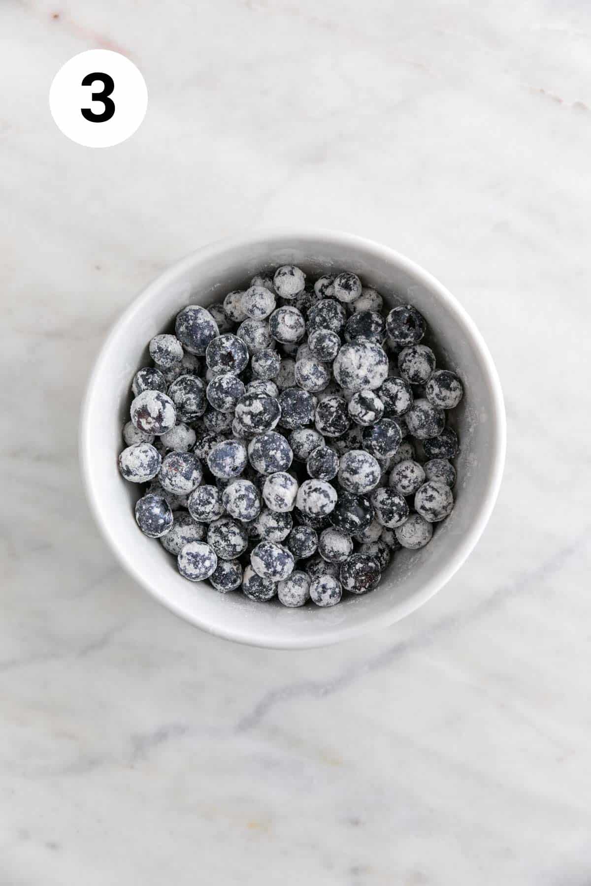 Blueberries coated in flour in a mixing bowl.
