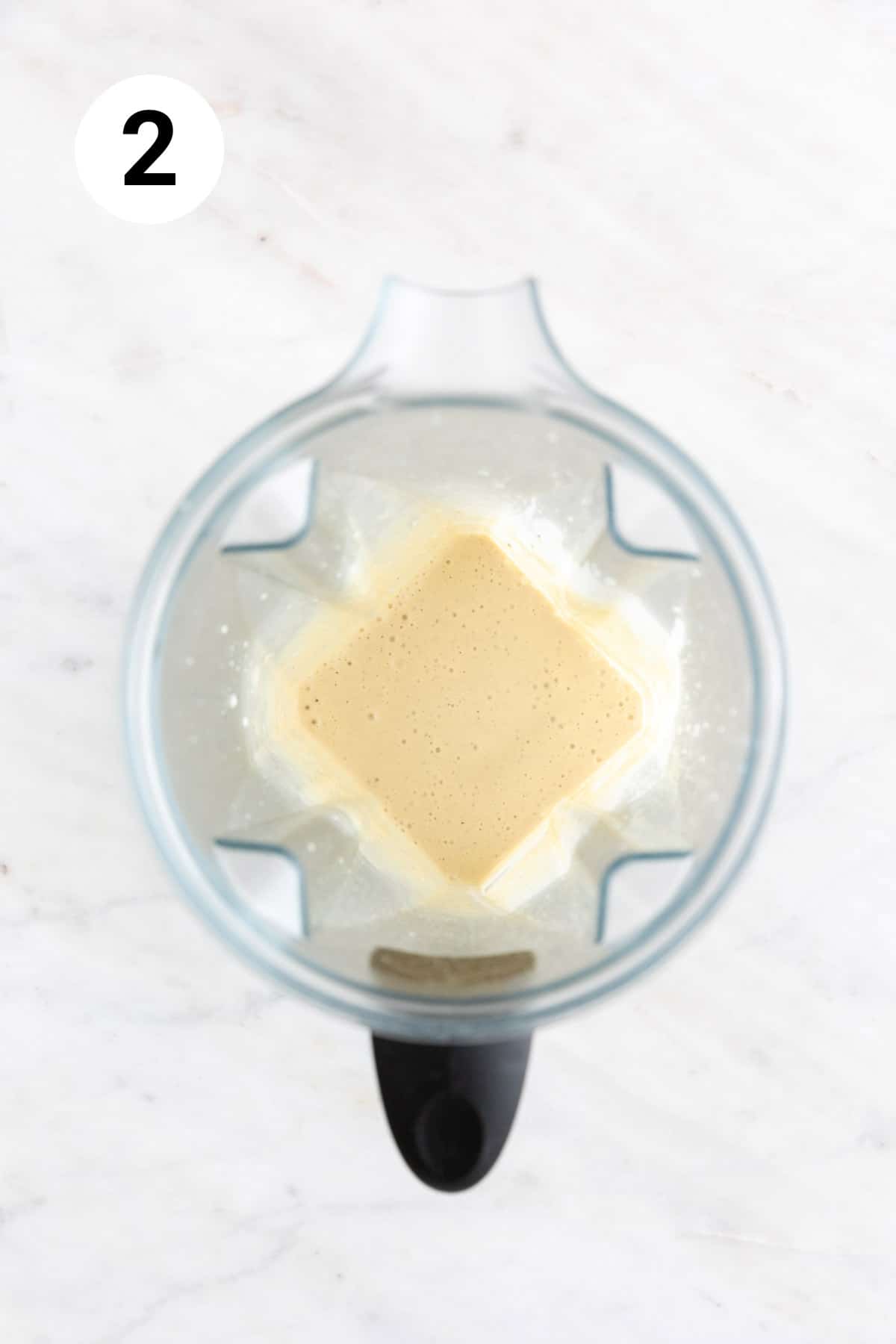 Blended vegan Caesar dressing ingredients in a high-speed blender jar.
