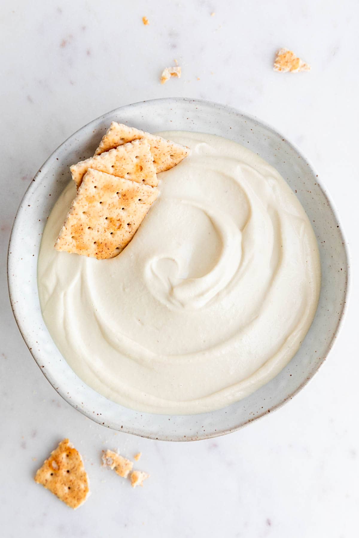 Bowl of vegan cashew cheese with crackers around.