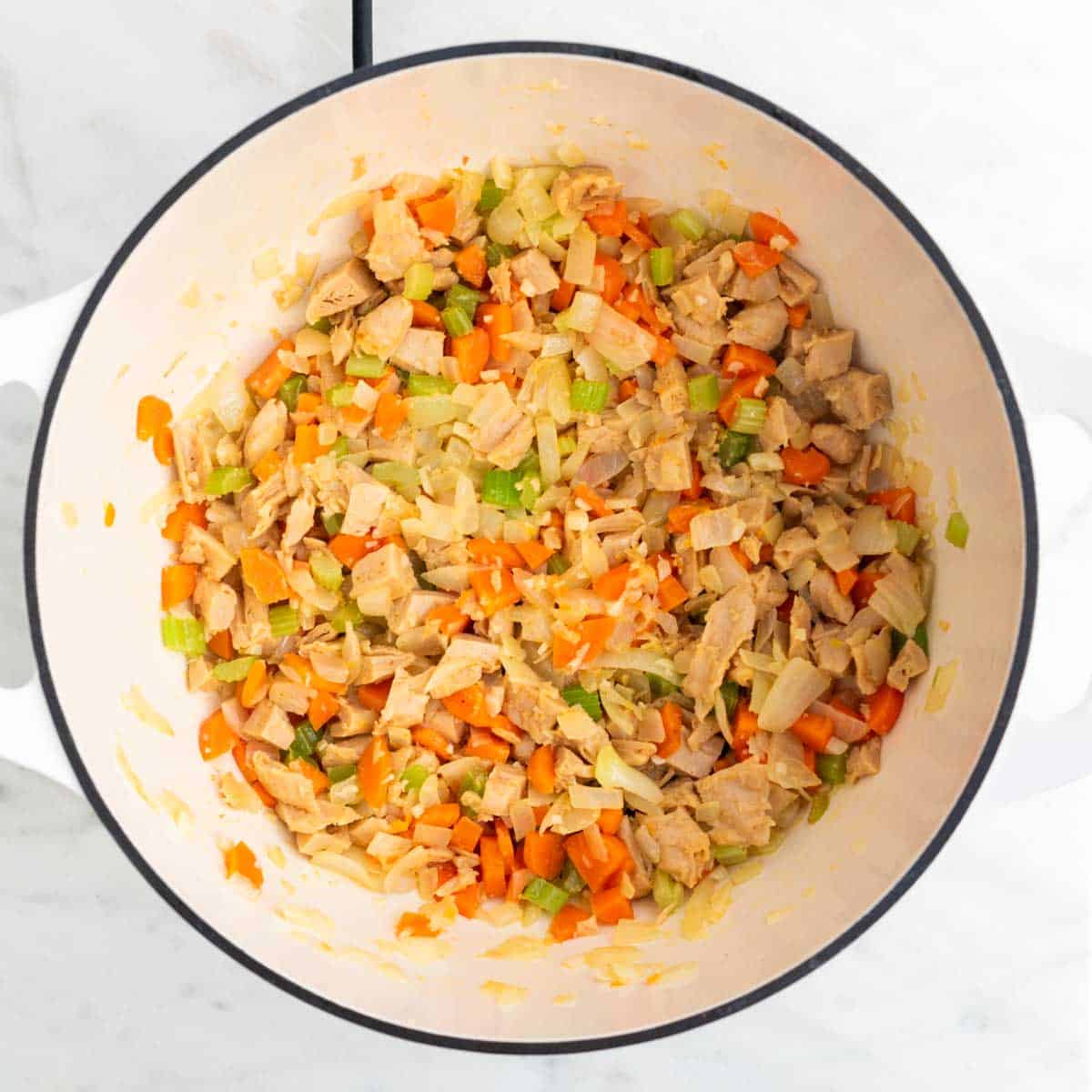 Sautéed vegetables and vegan chicken in a large pot.