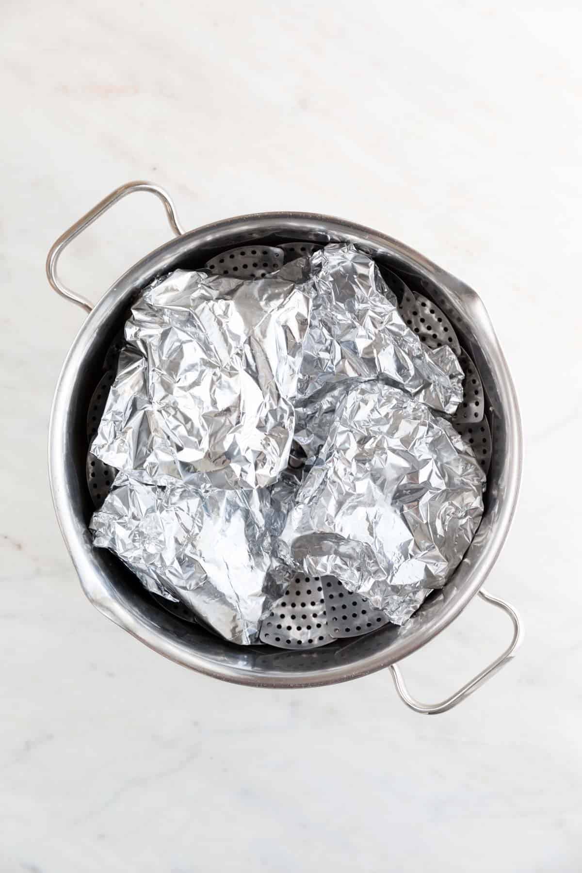 The 4 pieces wrapped in aluminum foil and place onto a steamer basket inside a large pot.