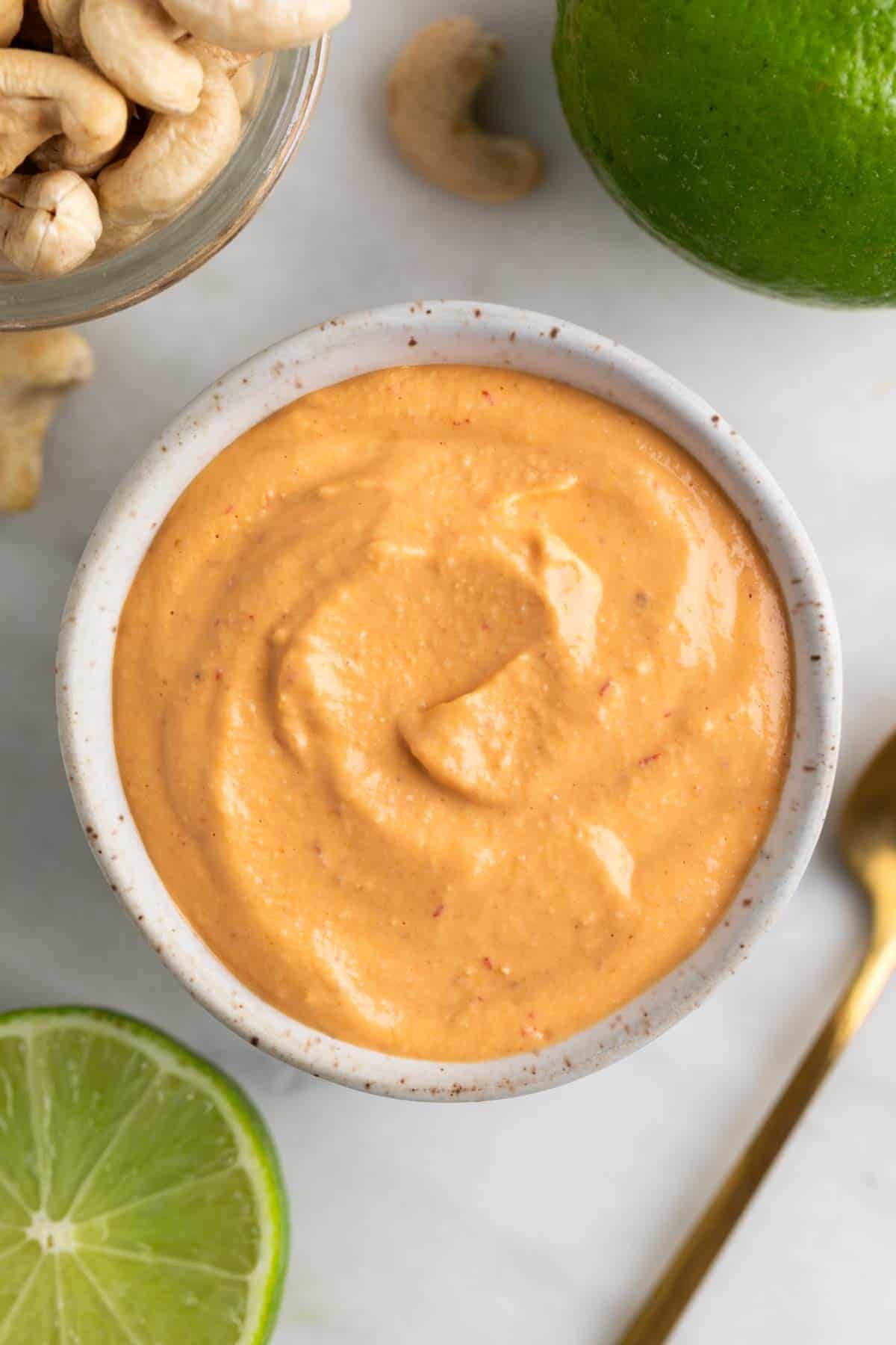 Vegan chipotle sauce in a bowl with ingredients and a spoon around it.