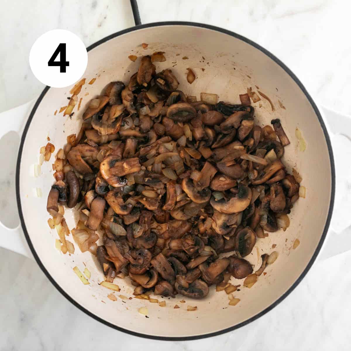 Mushrooms, garlic, onion, and wine sautéed in a large pot.