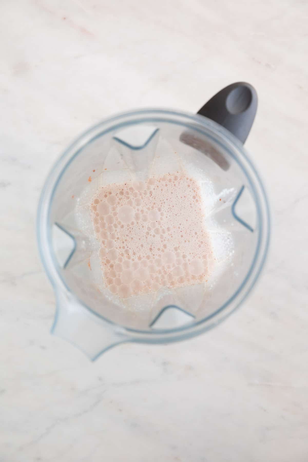 A blender with all the vegan eggnog ingredientes already blended.