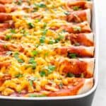 Vegan enchiladas in a baking dish garnished with fresh chopped cilantro.