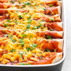 Vegan enchiladas in a baking dish garnished with fresh chopped cilantro.