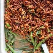 Baking dish of vegan green bean casserole with a spoon.