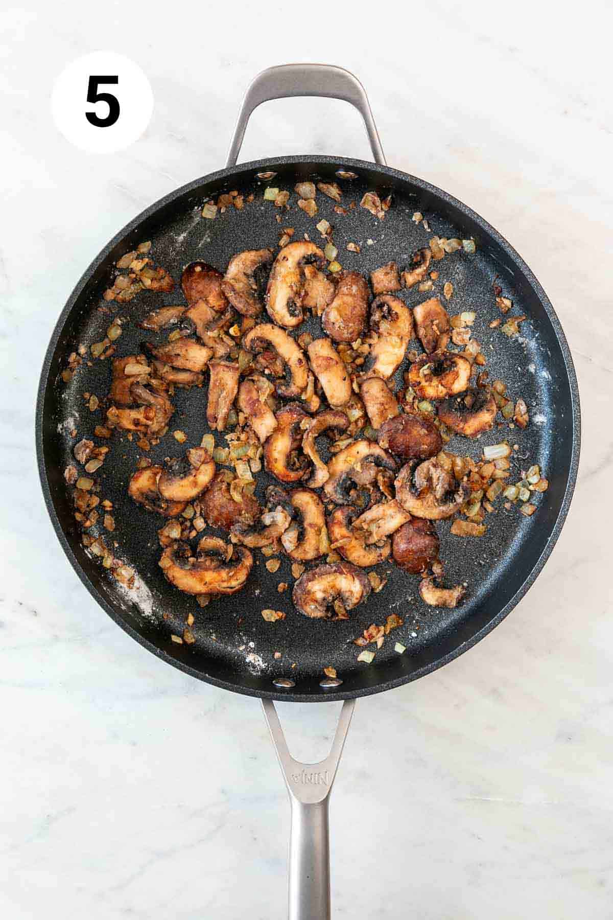 Onion, garlic, and mushrooms sautéed in a skillet with flour.