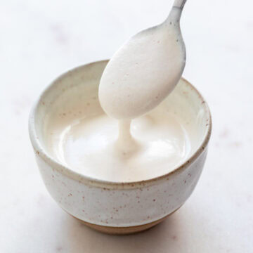 Spoon dipping into bowl of vegan heavy cream substitute.
