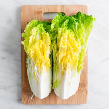 Half of cabbage cut into halves on a cutting board.