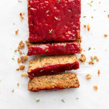 Sliced vegan lentil loaf adorned with fresh oregano.