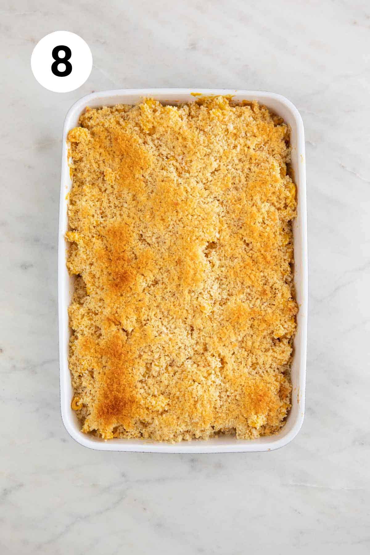 Baking dish with baked vegan mac and cheese topped with breadcrumbs.