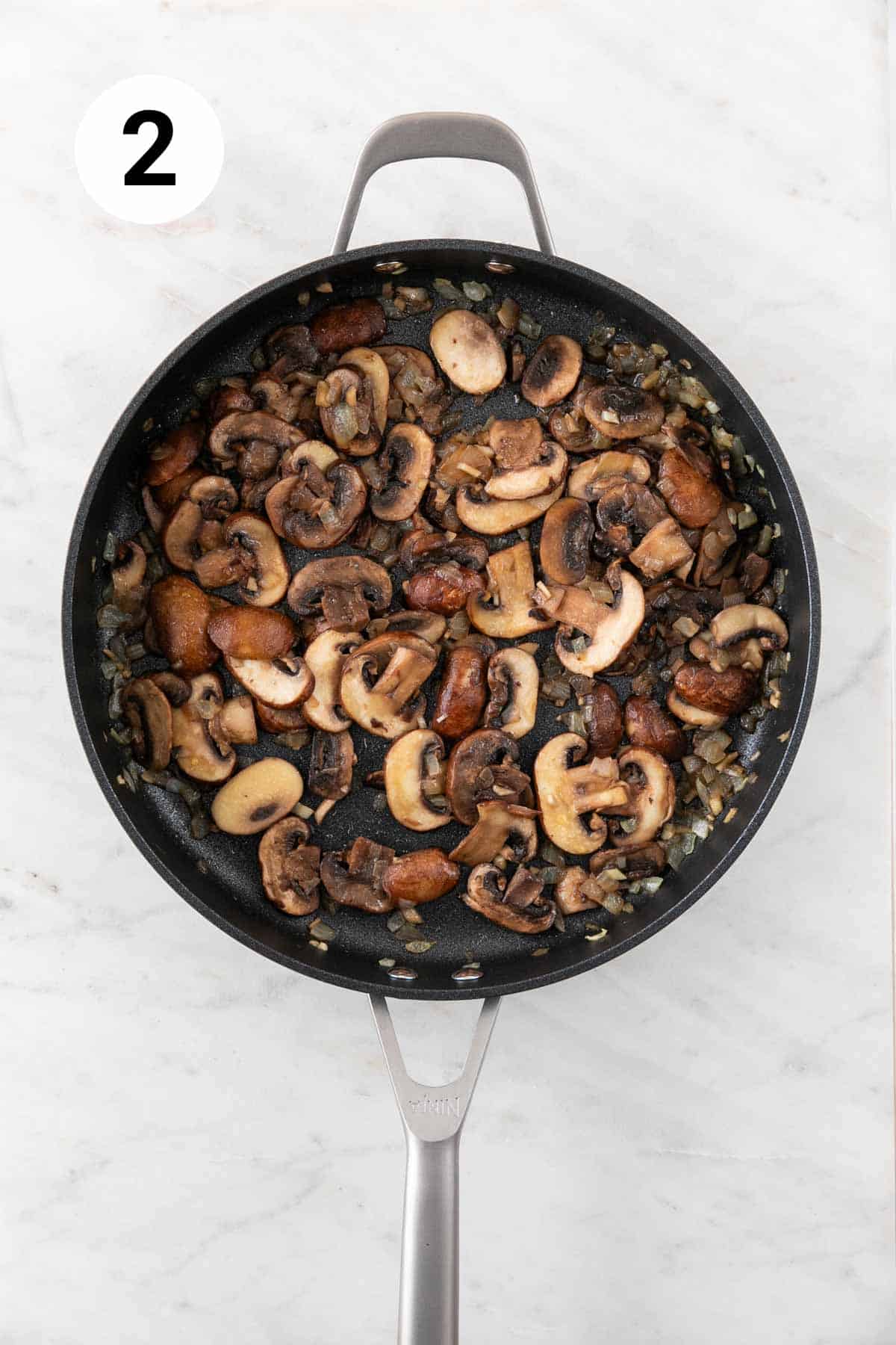 Onion, garlic, and mushrooms sautéed in a skillet.