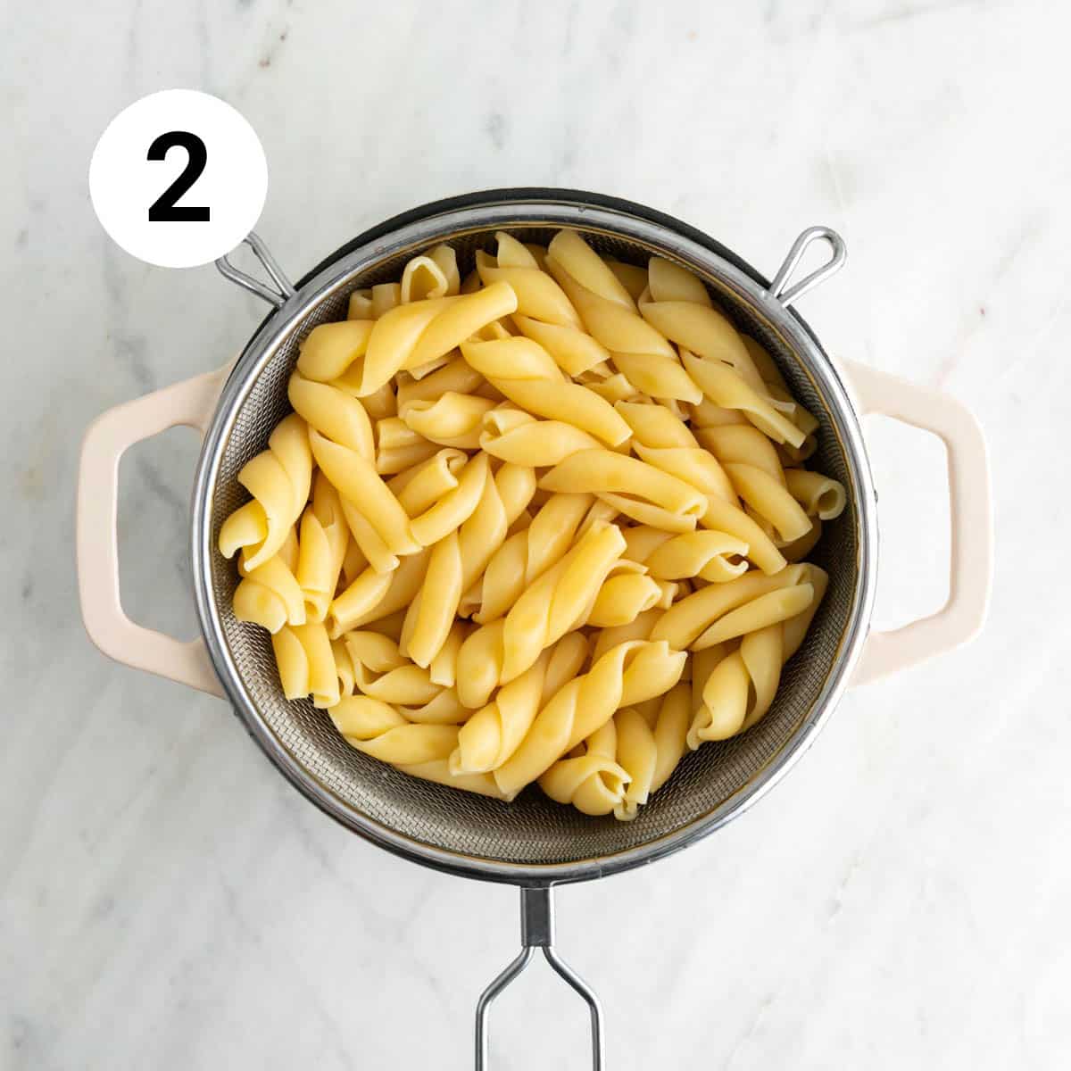 Pasta drained in a colander into a pot.