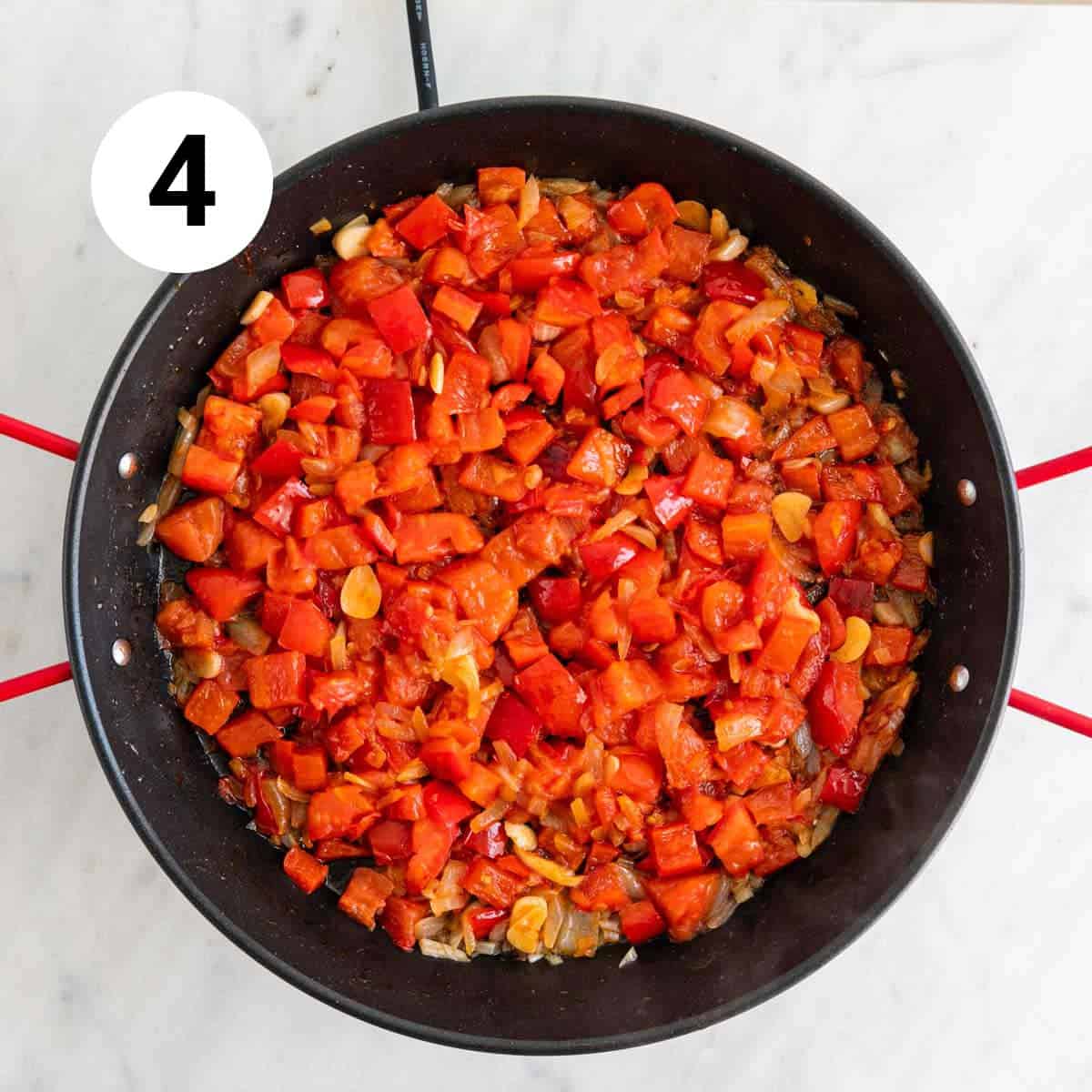 Onion, red bell pepper, garlic, tomatoes, and paprika sautéed in a paella pan.