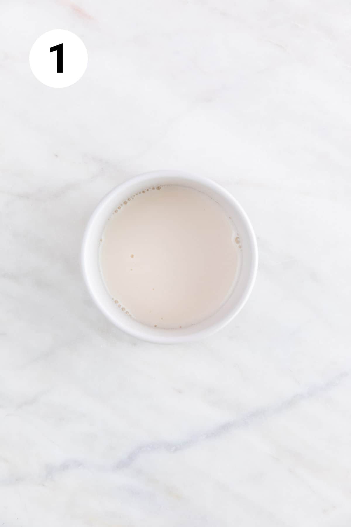 Mixture of non-dairy milk and apple cider vinegar in a small bowl.