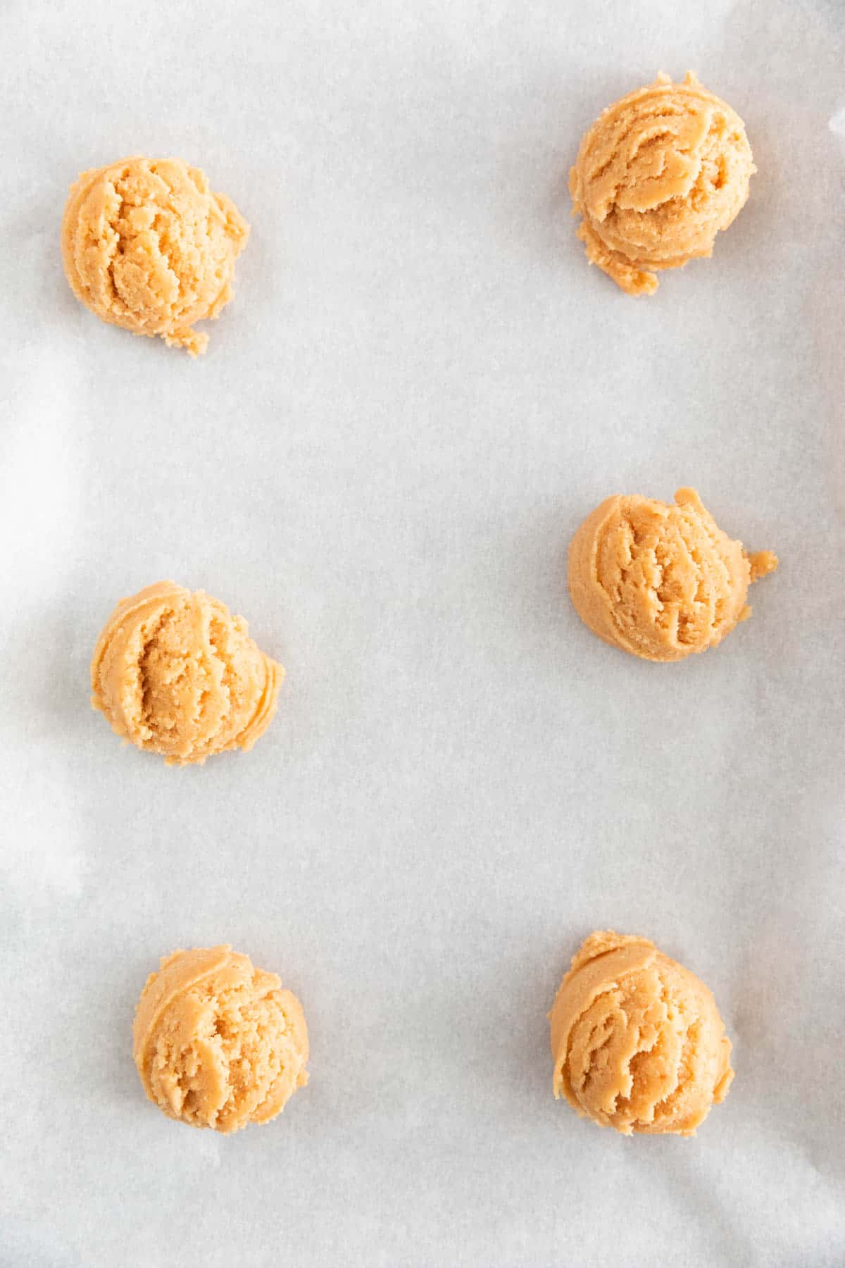 Cookie balls onto a lined baking sheet.