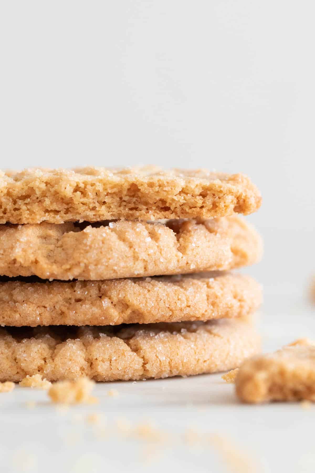 Vegan peanut butter cookies stacked up with the top cookie broken in half.