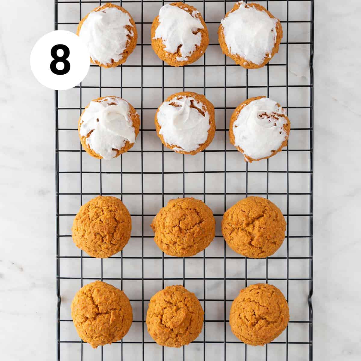 Baked vegan pumpkin cookies onto a cooling rack, some with frosting.