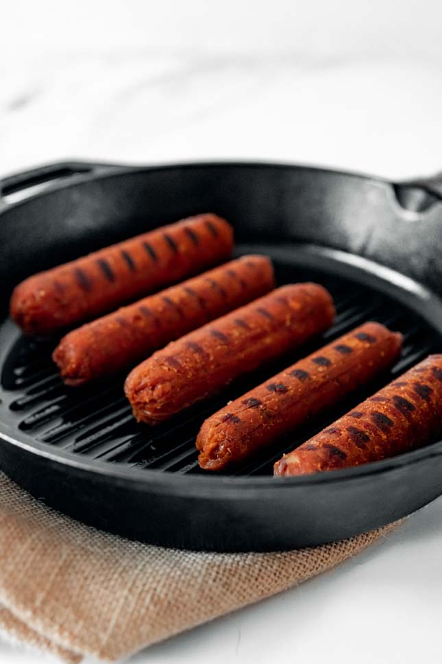 Photo of a skillet with some vegan sausages