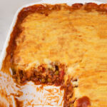 Photo of a vegan shepherd's pie casserole with one portion missing and the words vegan shepherd's pie