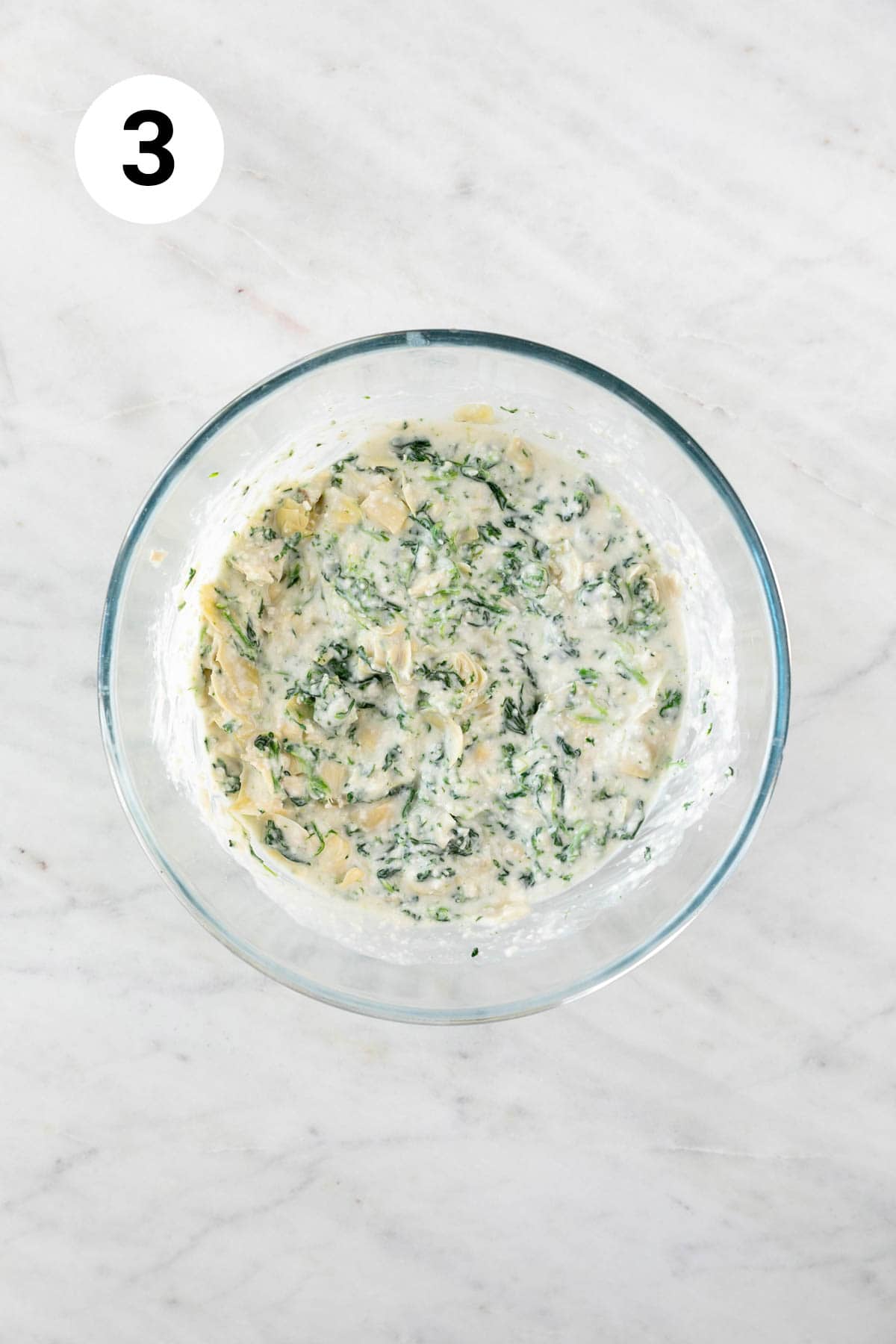 Vegan spinach artichoke dip in a bowl before baking.