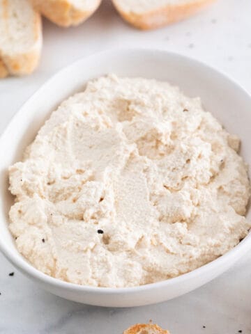 A bowl with vegan tofu ricotta cheese and some bread slices around.