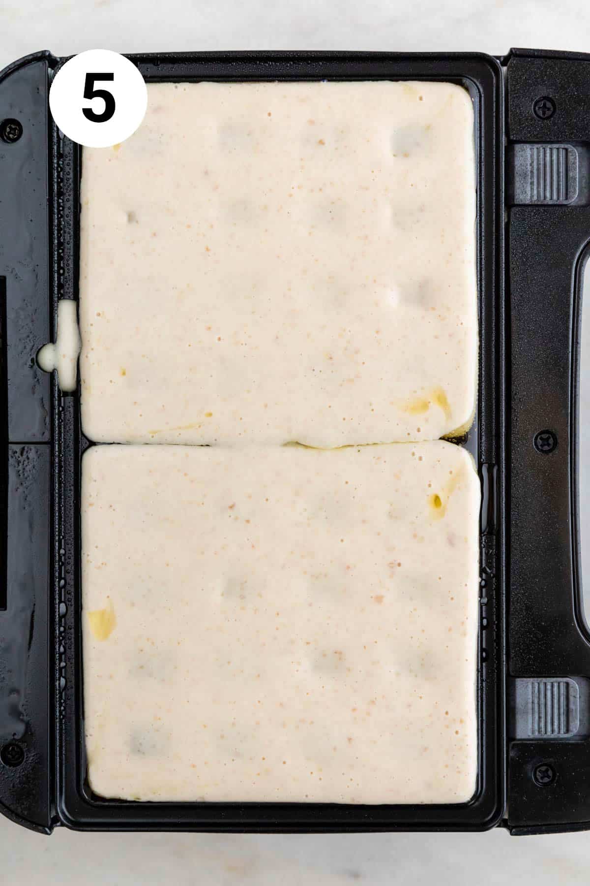 Vegan waffle batter poured onto a preheated waffle iron.