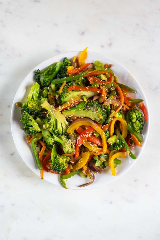 An overhead shot of a dish with veggie stir fry garnished with sesame seeds