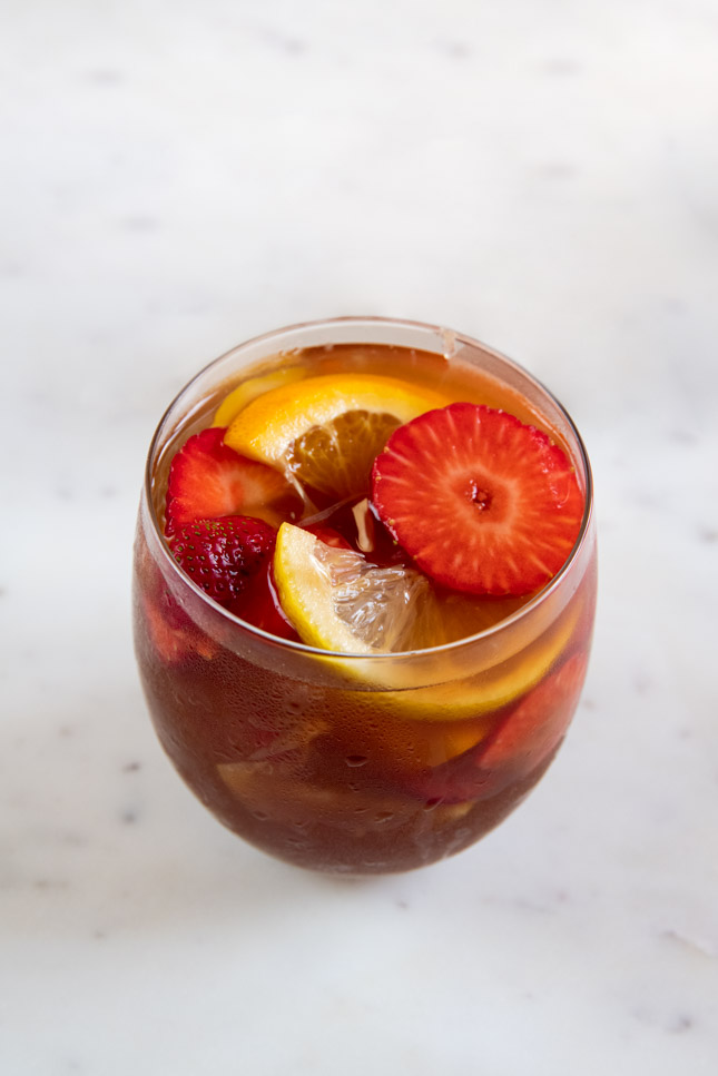 A picture of a glass with fresh fruit, ice cubes and white sangria